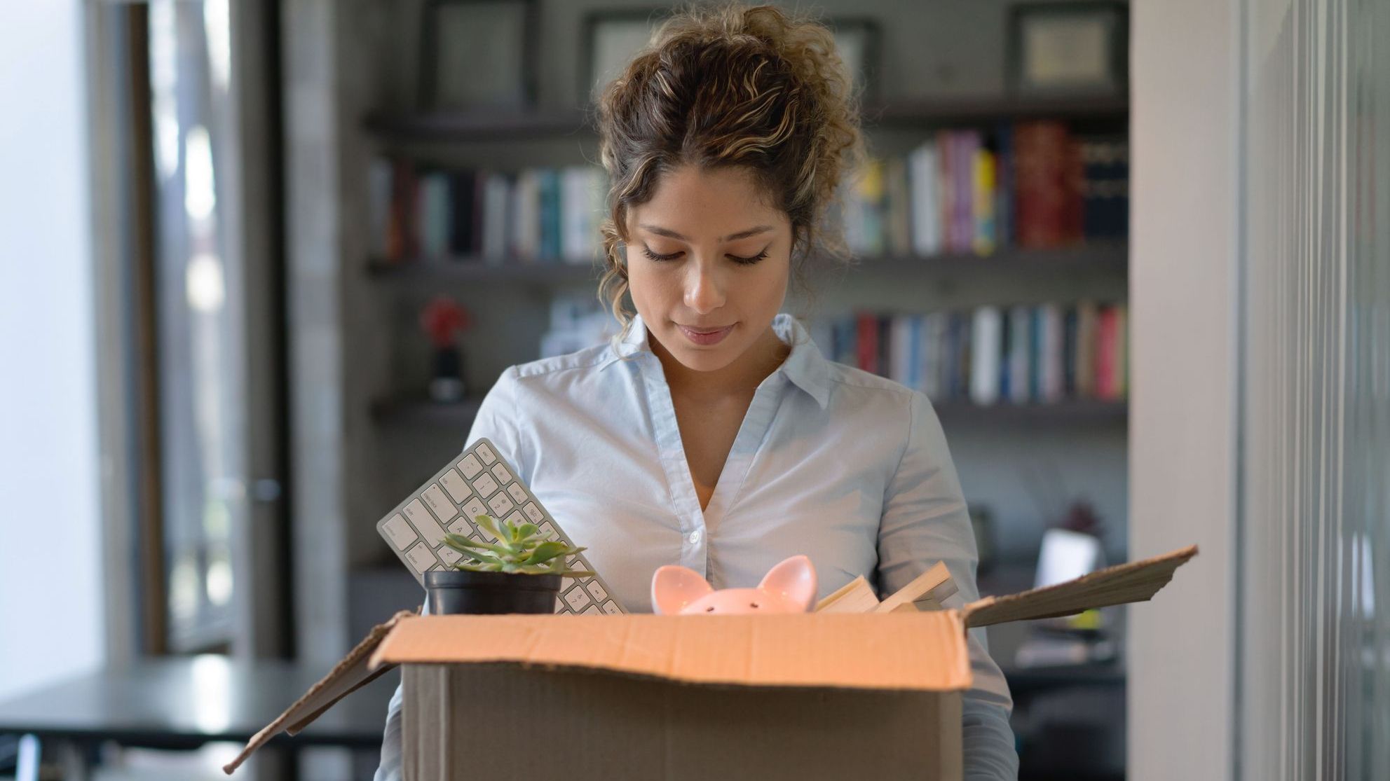 An employee leaves her office after being laid off from her company.