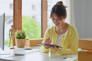 Small business owning woman sitting at a desk smiling while looking at a template going over her small business credit card debt.