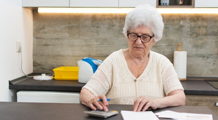 A woman who appears to be in her 70s or 80s using a calculator. 